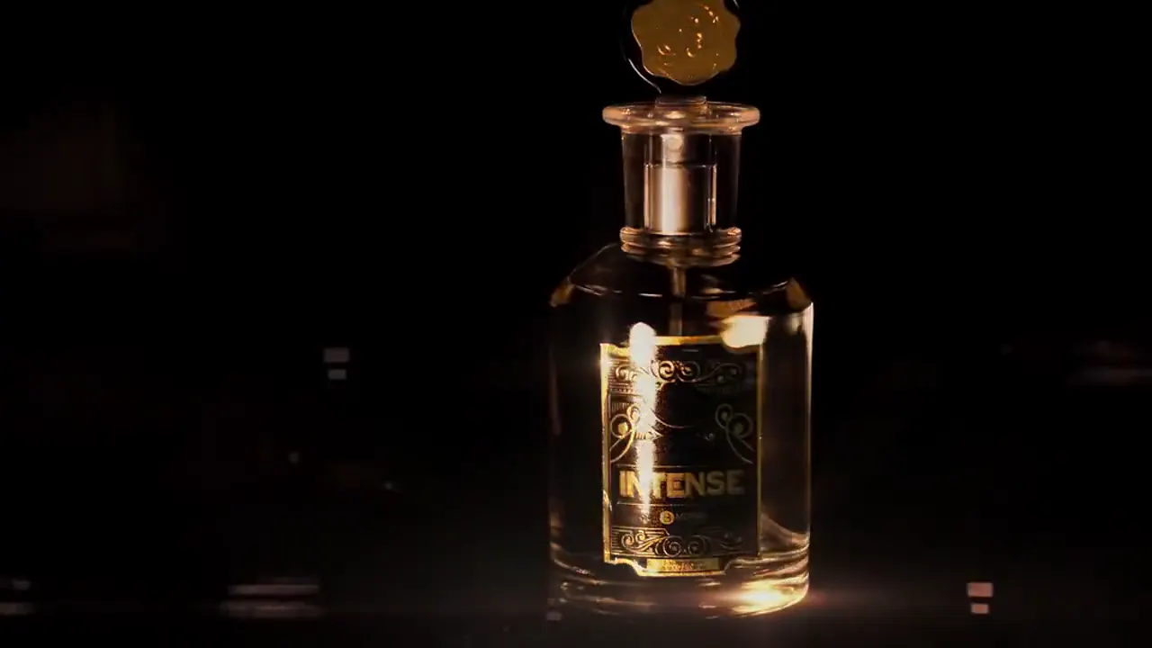 Comercial de perfume: frasco iluminado sobre fondo negro